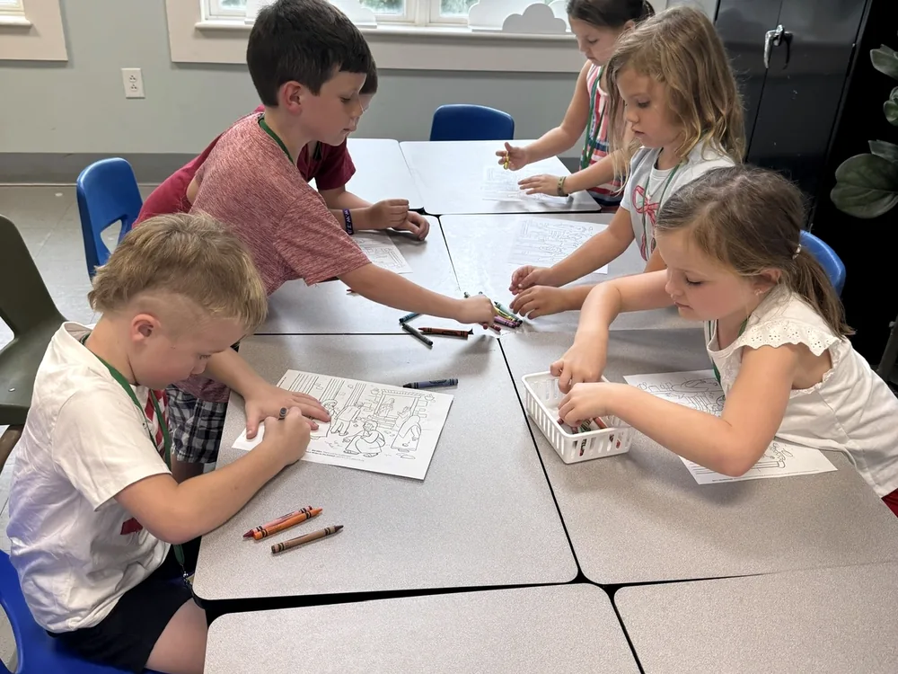 Children seated around a low table in a St. Paul’s classroom, drawing and working on a craft together.