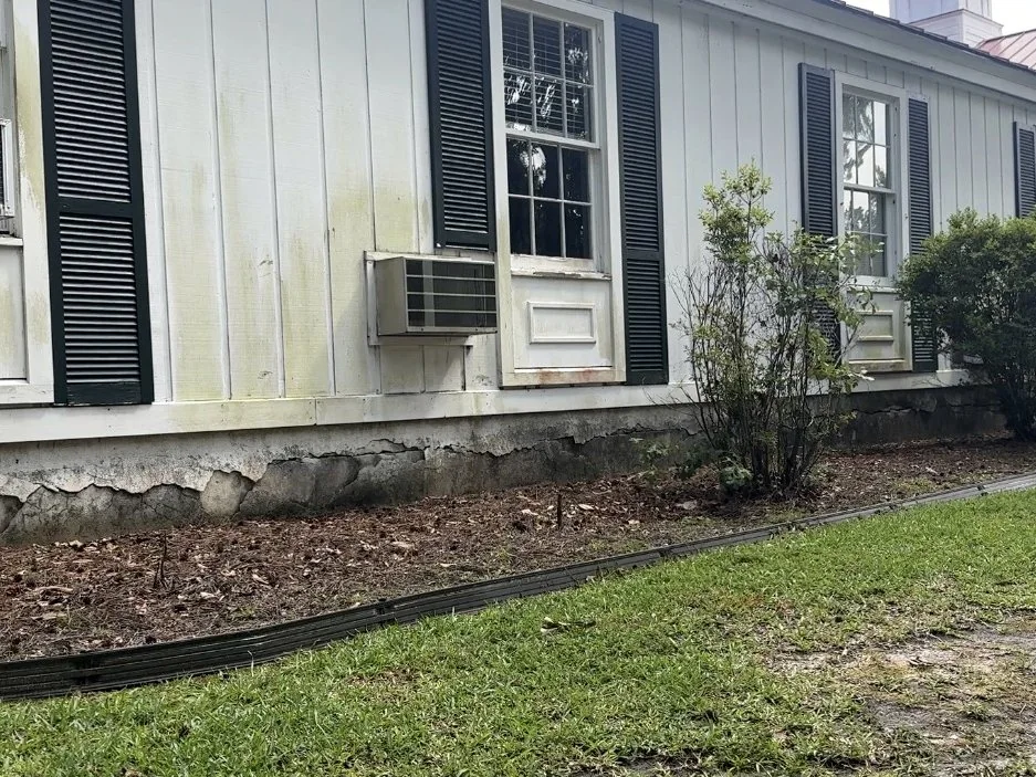 Weathered exterior siding and trim on Skardon Hall showing paint failure and deterioration.