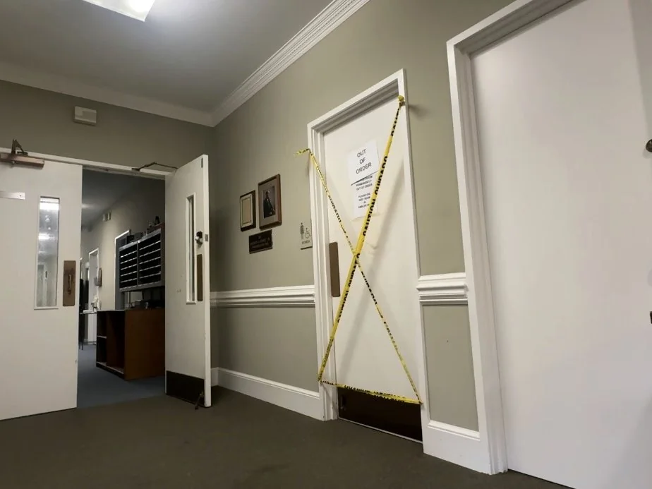 An interior hallway in Skardon Hall showing damaged wall surfaces and dated construction.