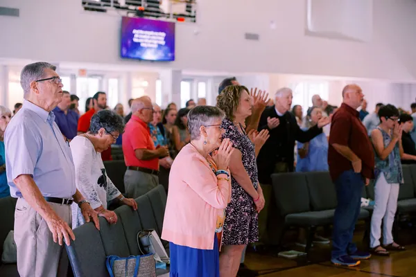 Members of St.&nbsp;Paul’s standing together in worship, some with hands raised, others with hands folded in prayer.