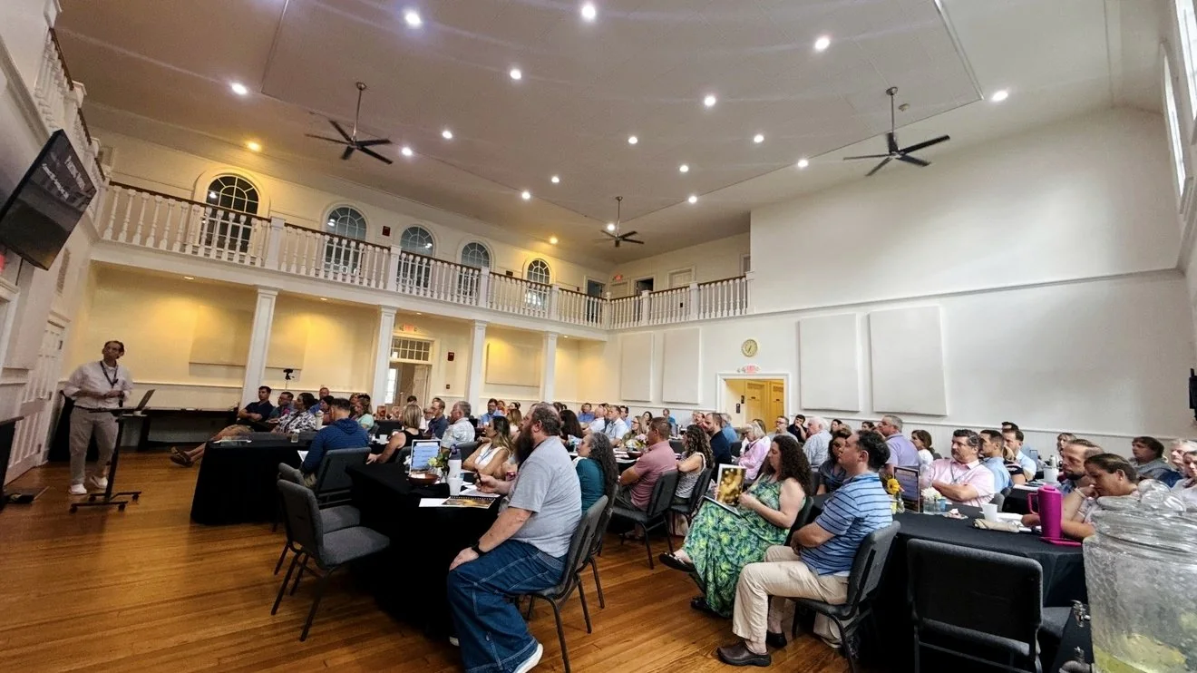 Parishioners seated at round tables in the parish hall, talking together over a shared meal.