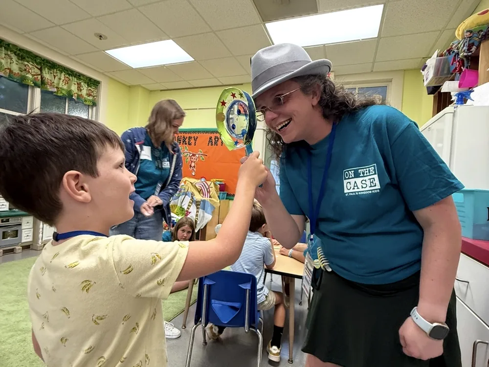A volunteer kneeling beside a child during a vacation Bible school morning at St. Paul’s.